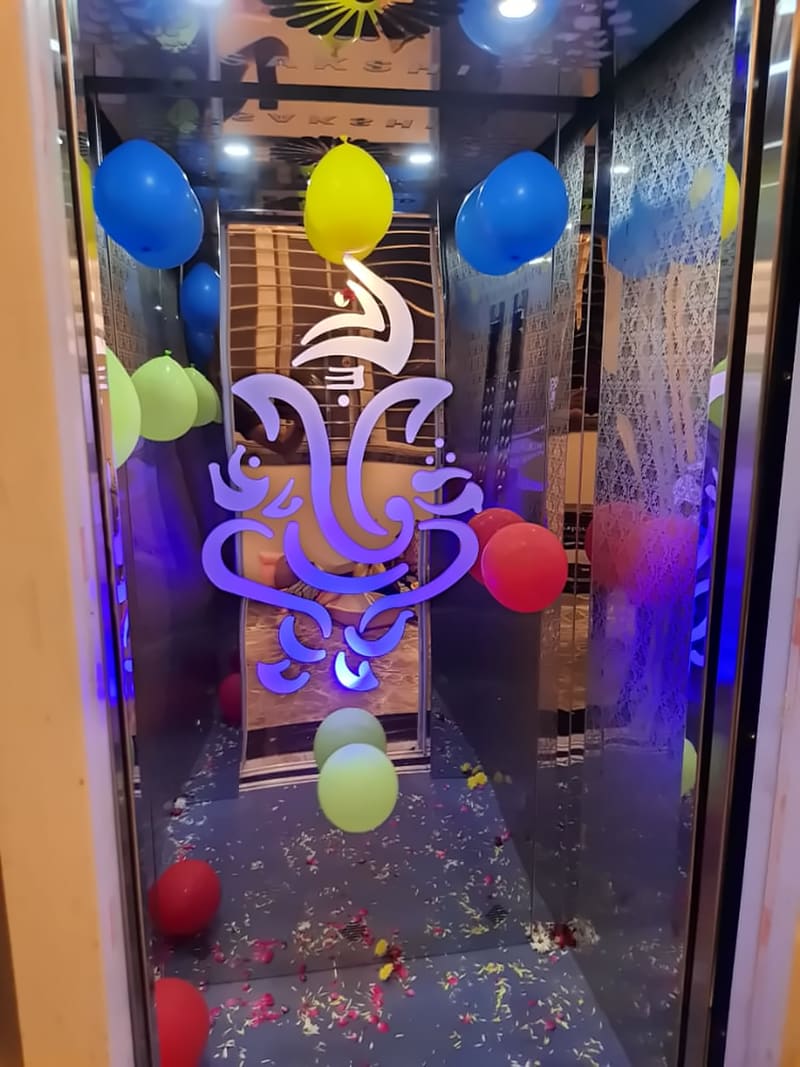 Lift cabin with an illuminated Ganesha motif etched into the rear wall
