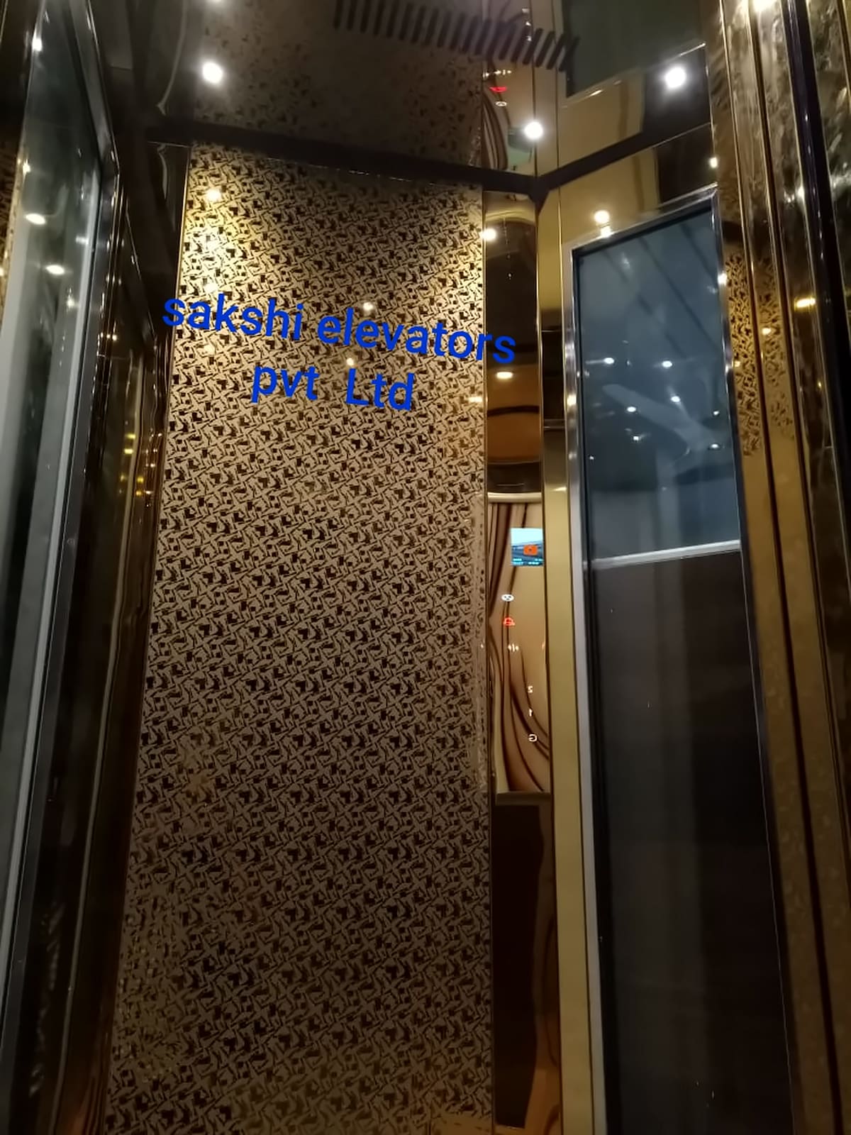 Sakshi lift cabin with a gold laser-cut jali rear panel and glass side walls