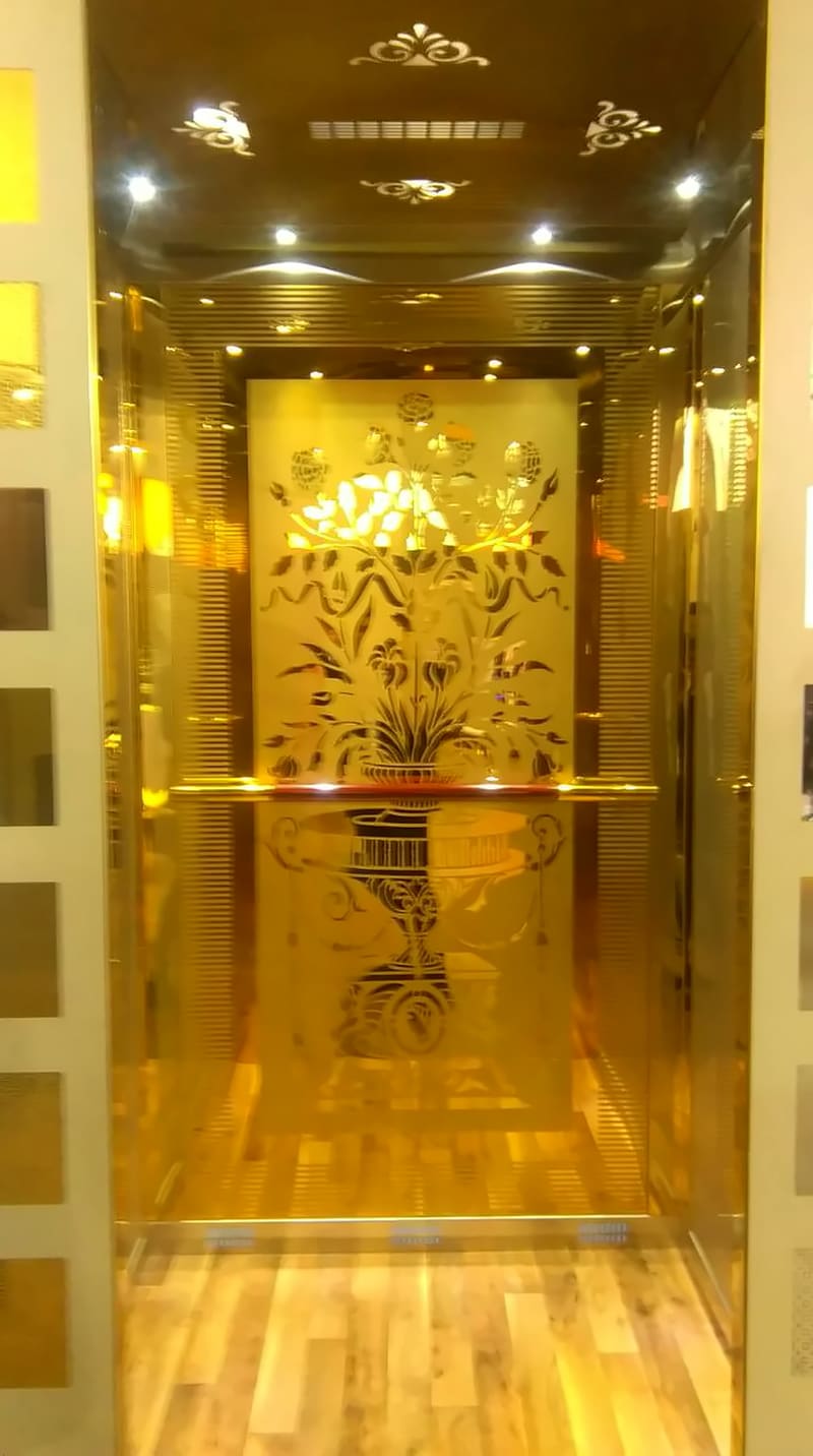 Sakshi lift cabin with gold mirror-finish walls, an etched rear panel and wooden flooring